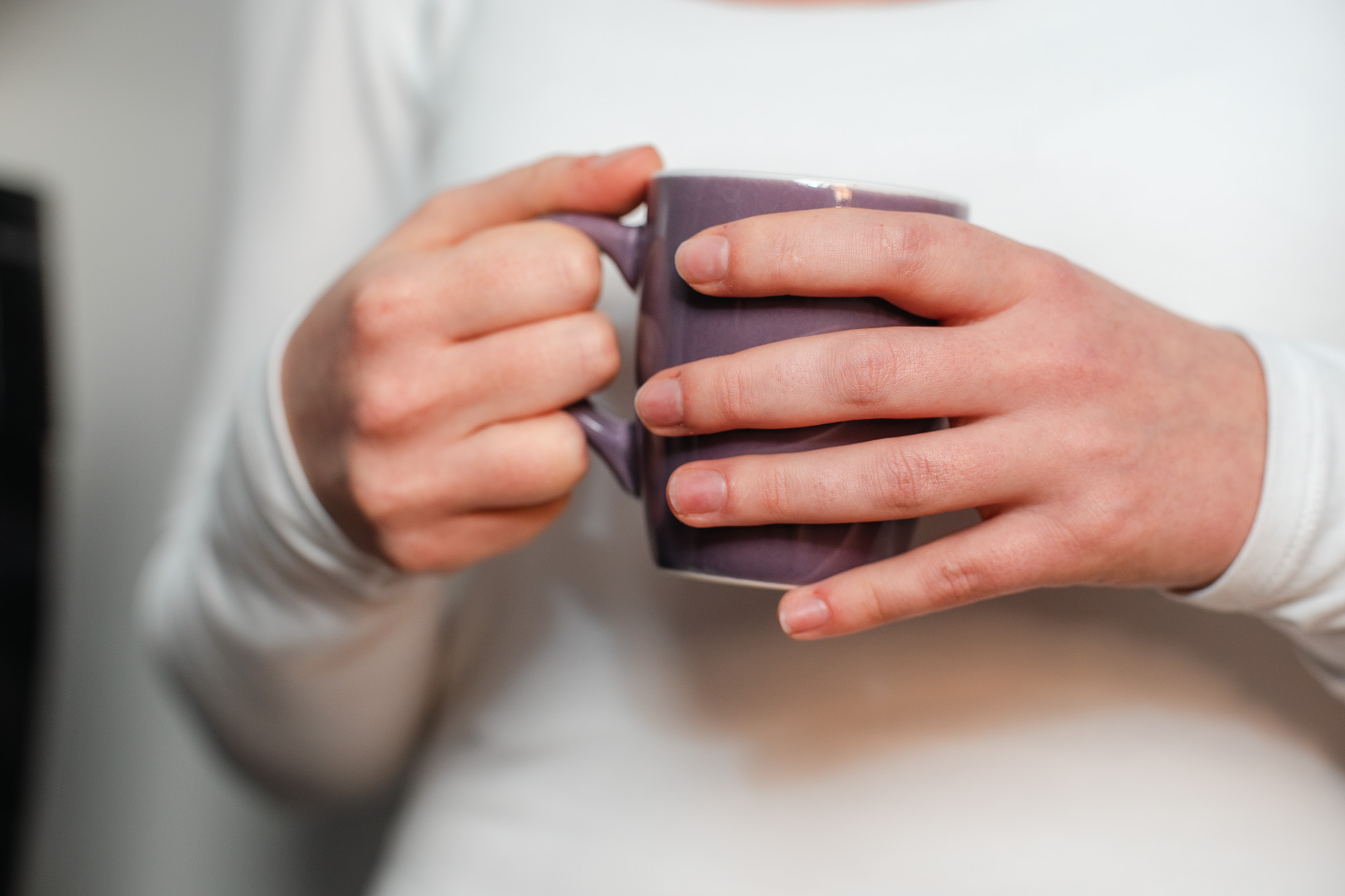 Nahaufnahme zweier Hände mit einer lila Kaffeetasse – kleine Auszeit im Arbeitsalltag der Kanzlei Cordula Groß in Ilmenau und Mühlhausen.