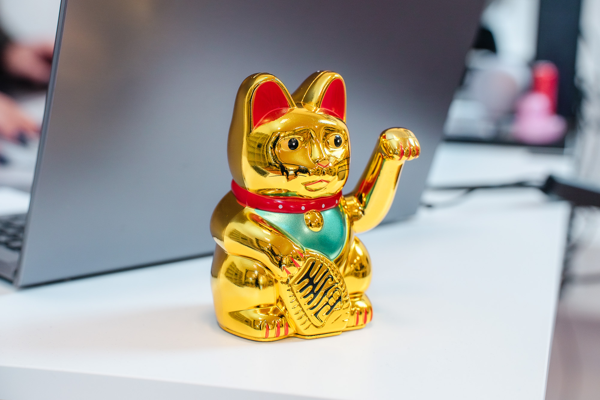 Eine goldene Winkekatze steht auf einem Schreibtisch in der Steuerkanzlei Cordula Groß – ein charmantes Detail im modernen Arbeitsumfeld.