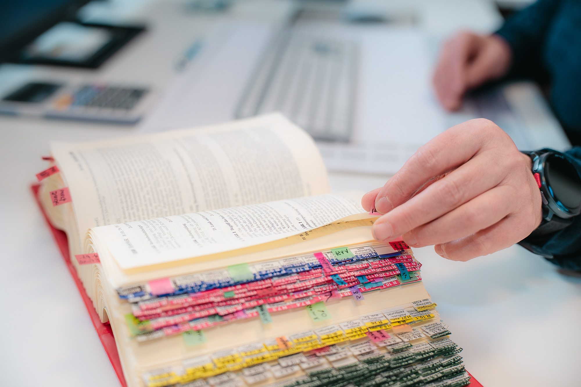 Eine Hand blättert in einem umfangreich markierten Gesetzbuch – präzises Arbeiten mit steuerrechtlichem Fachwissen in der Kanzlei Cordula Groß.